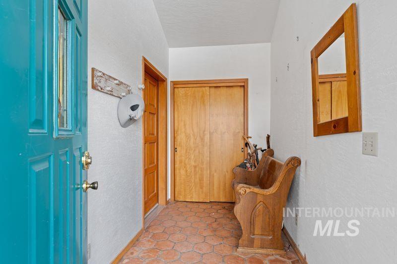 Doorway with a textured wall and light tile patterned floors