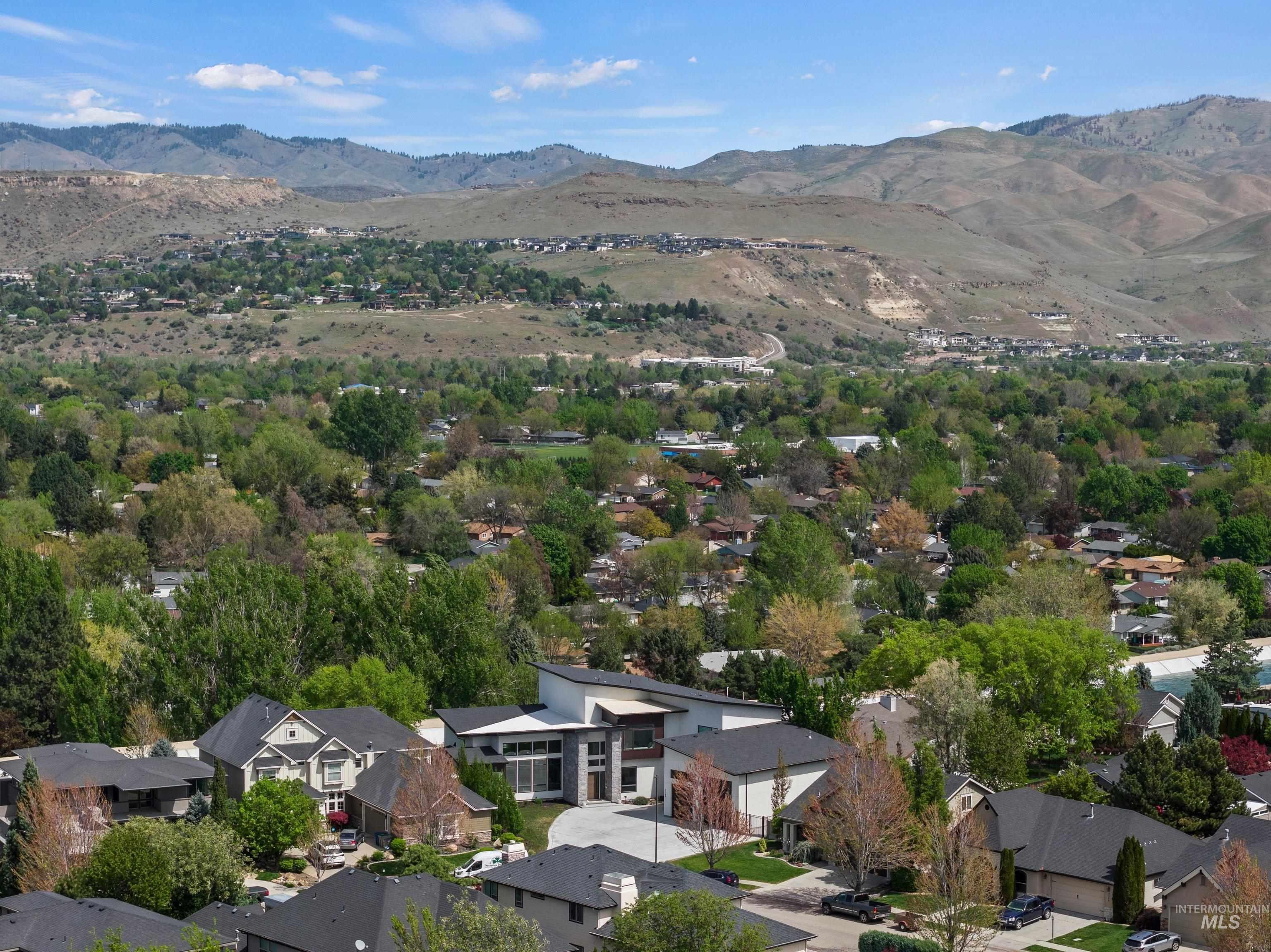 Expansive neighborhood featuring varied architectural styles and mature trees, set against a backdrop of distant mountains