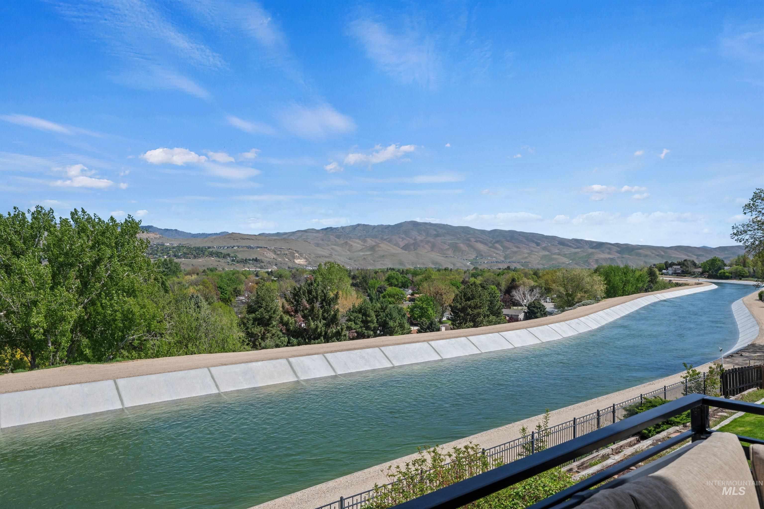 Expansive water channel bordering the property, framed by a black metal railing