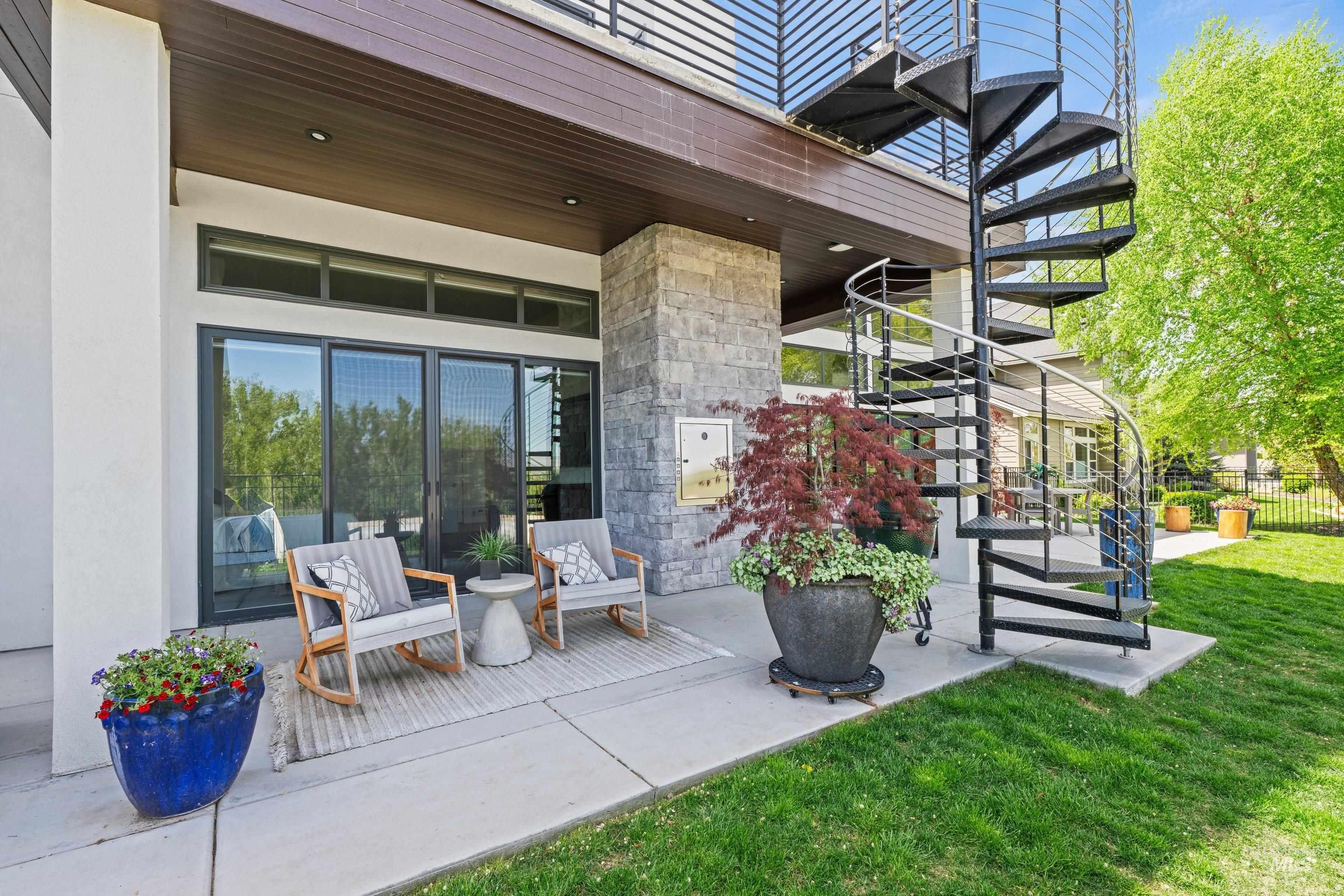 Exterior patio with a black metal spiral staircase, stone facade, and large sliding glass doors