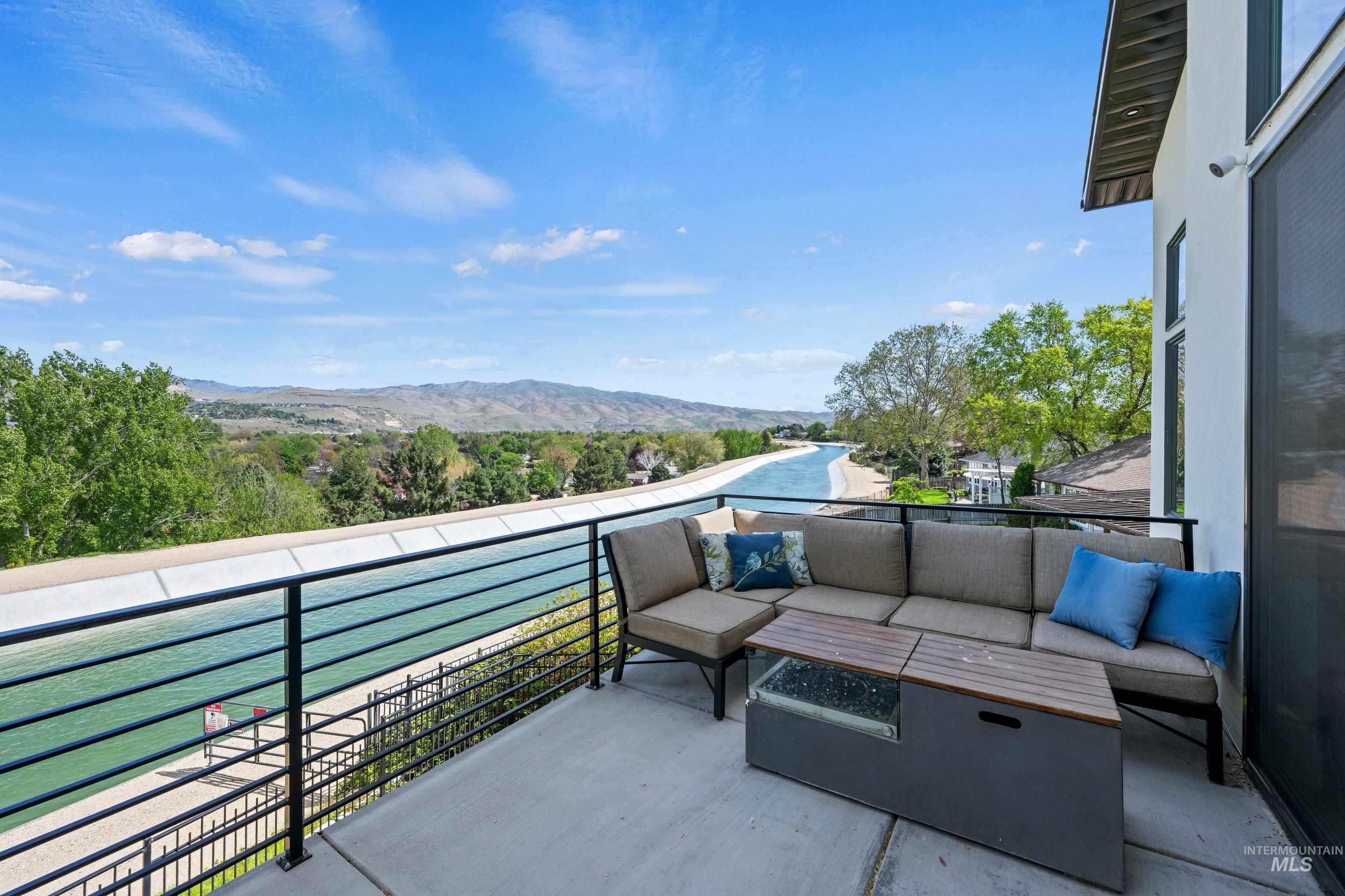 Balcony overlooking a waterway with mountain and tree-lined terrain in the distance