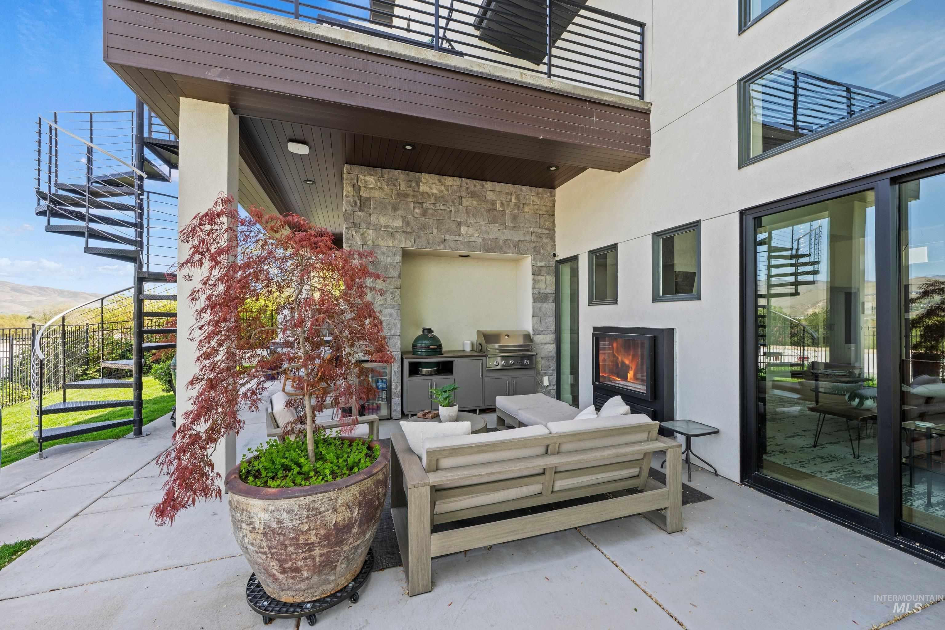 Spacious outdoor patio featuring a built-in grill station with stone accent wall, an outdoor fireplace, and a covered ceiling with recessed lighting