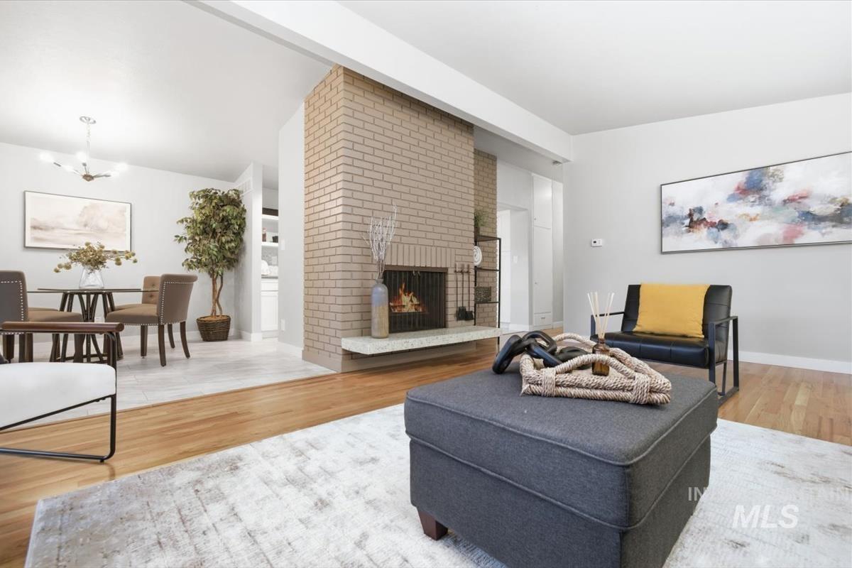 Living room with a fireplace, light wood-type flooring, and hanging lights