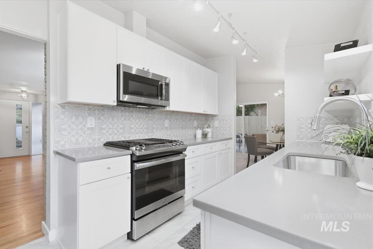 Kitchen featuring stainless steel appliances, white cabinets, and decorative backsplash