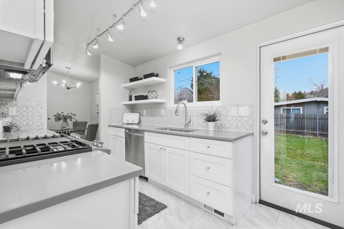 Kitchen with backsplash, white cabinets, open shelves, dishwasher, and extractor fan
