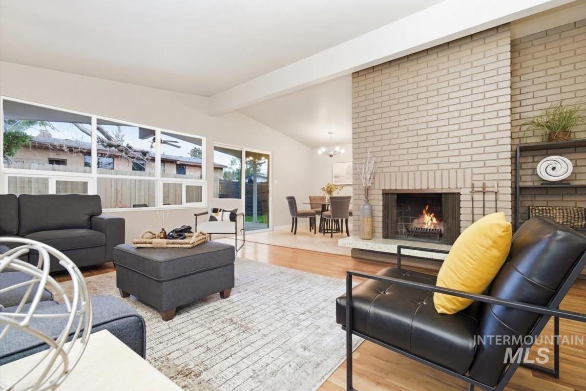 Living room featuring beam ceiling, wood finished floors, and a fireplace