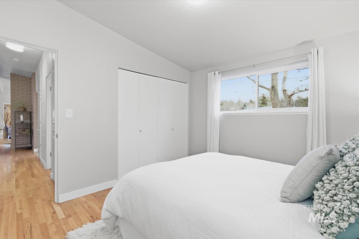 Bedroom featuring vaulted ceiling, light wood finished floors, and a closet