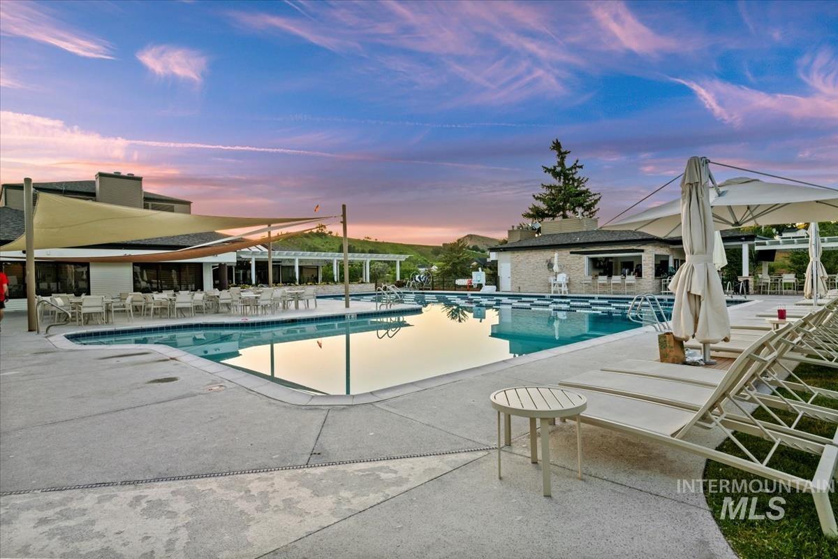 Pool at dusk featuring a community pool and a patio area