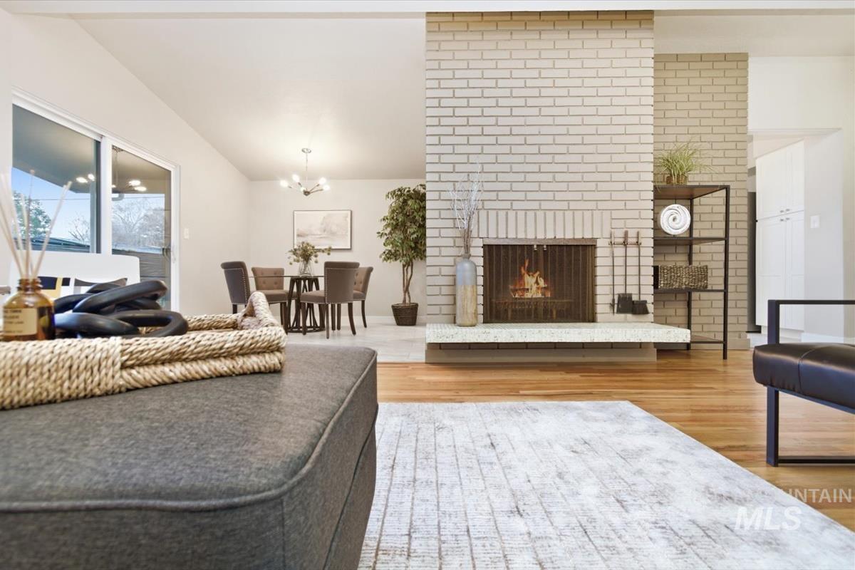 Living room with light wood-style flooring, a brick fireplace, and hanging lights
