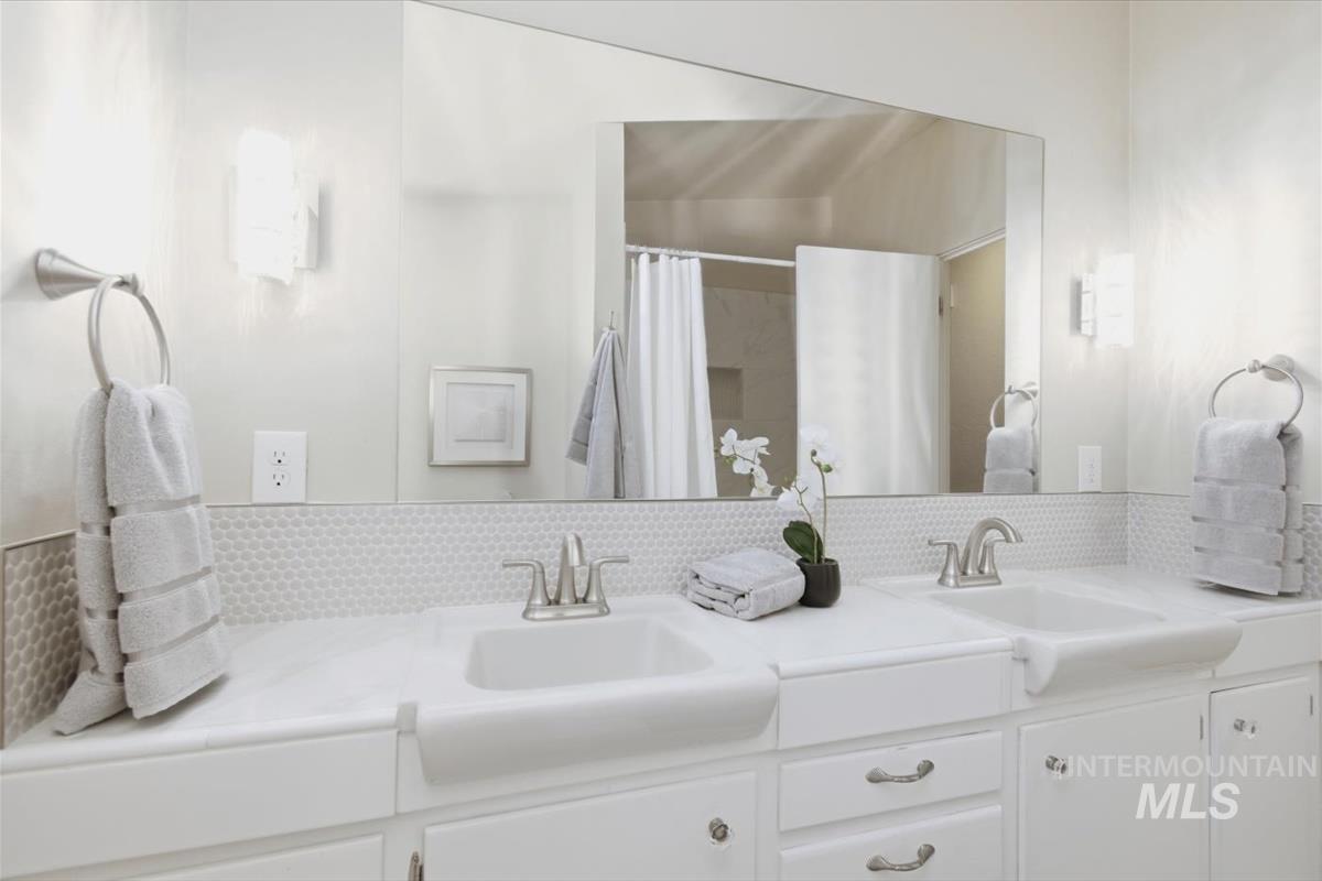 Full bath with double vanity and a shower with curtain