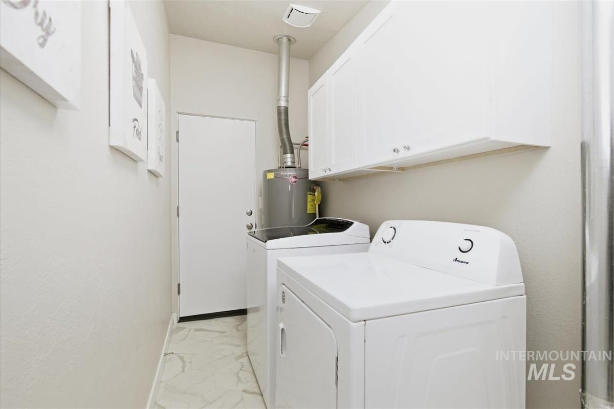 Laundry room featuring cabinet space, independent washer and dryer, water heater, and light marble finish floors