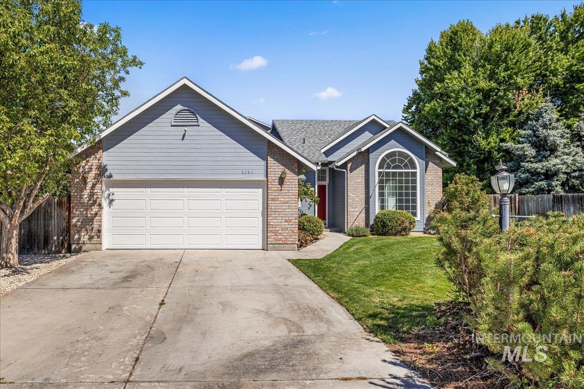 Ranch-style home featuring an attached garage, driveway, and brick siding