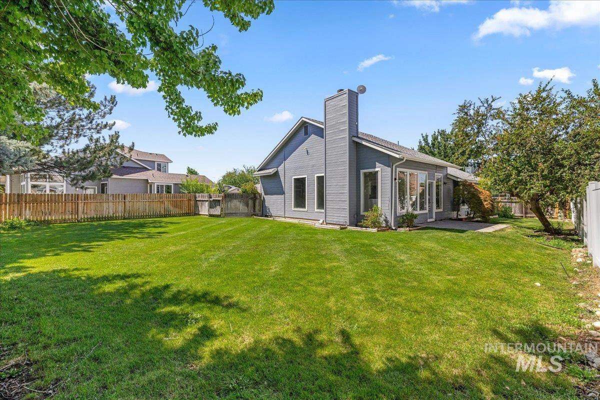 Back of house featuring a fenced backyard, a chimney, and a patio