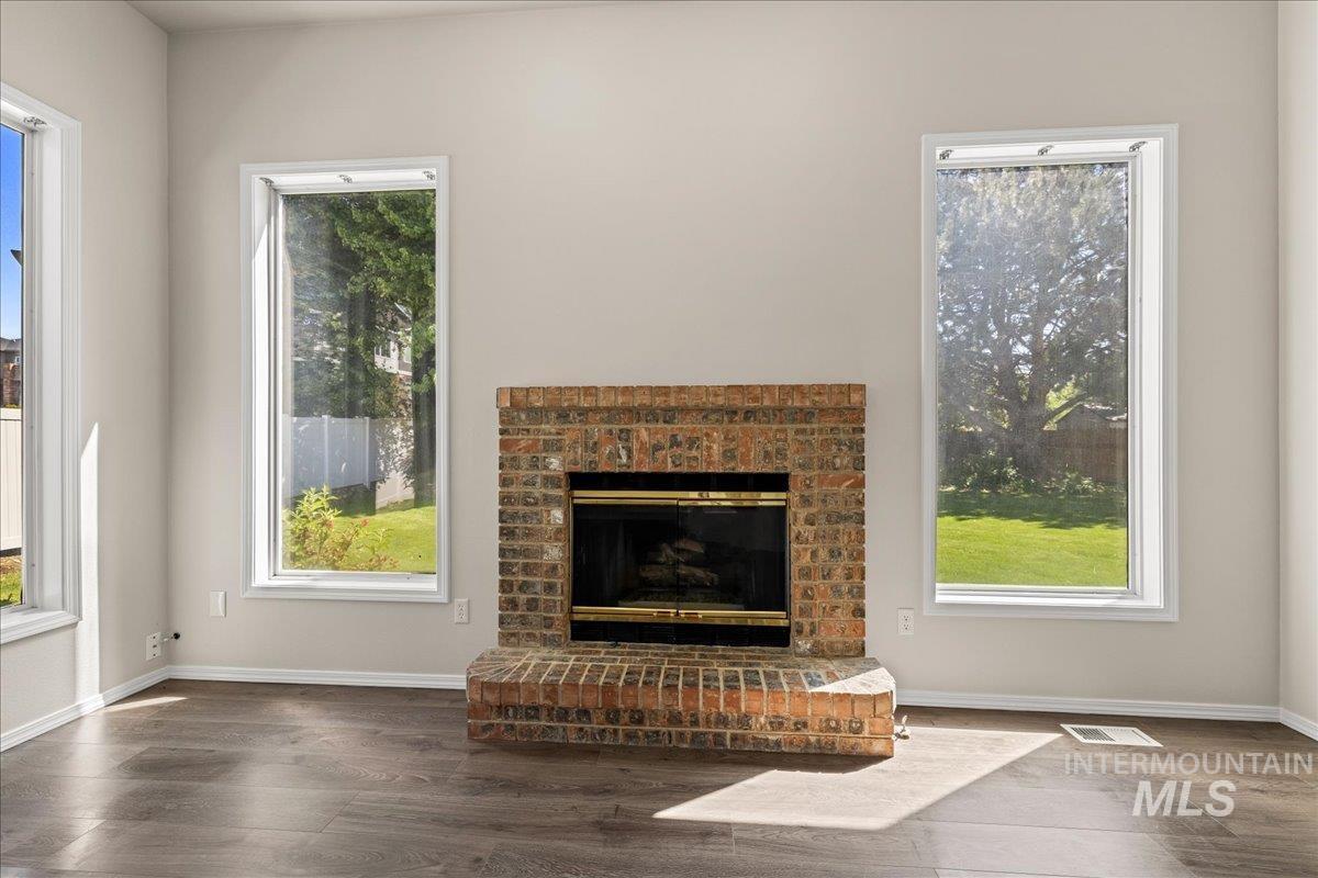 Unfurnished living room with a fireplace, wood finished floors, and plenty of natural light