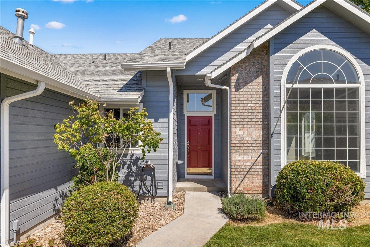 Entrance to property featuring roof with shingles and brick siding