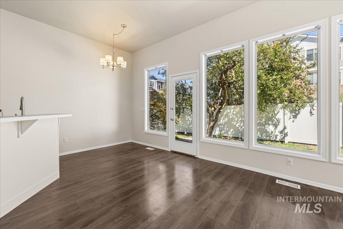 Unfurnished dining area with dark wood-style flooring and a chandelier