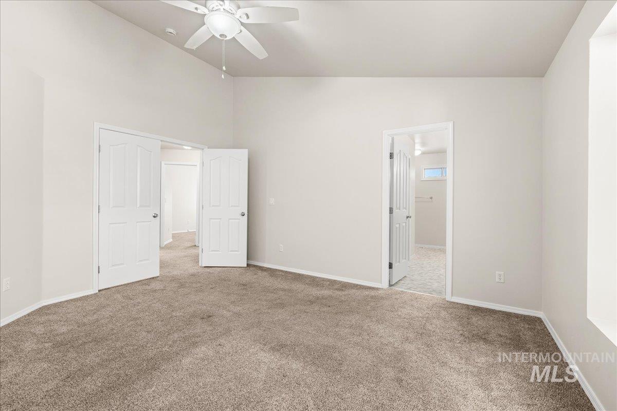 Unfurnished bedroom with carpet, vaulted ceiling, and ceiling fan