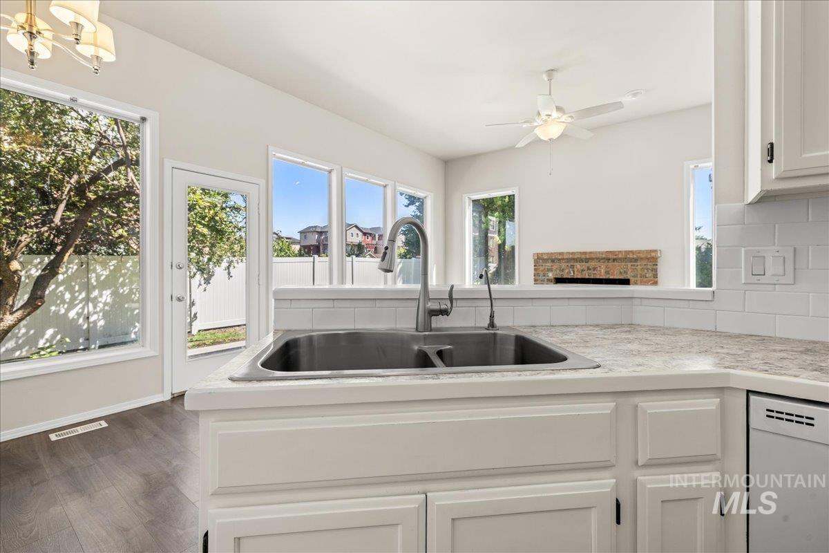 Kitchen with white cabinetry, white dishwasher, light countertops, and plenty of natural light