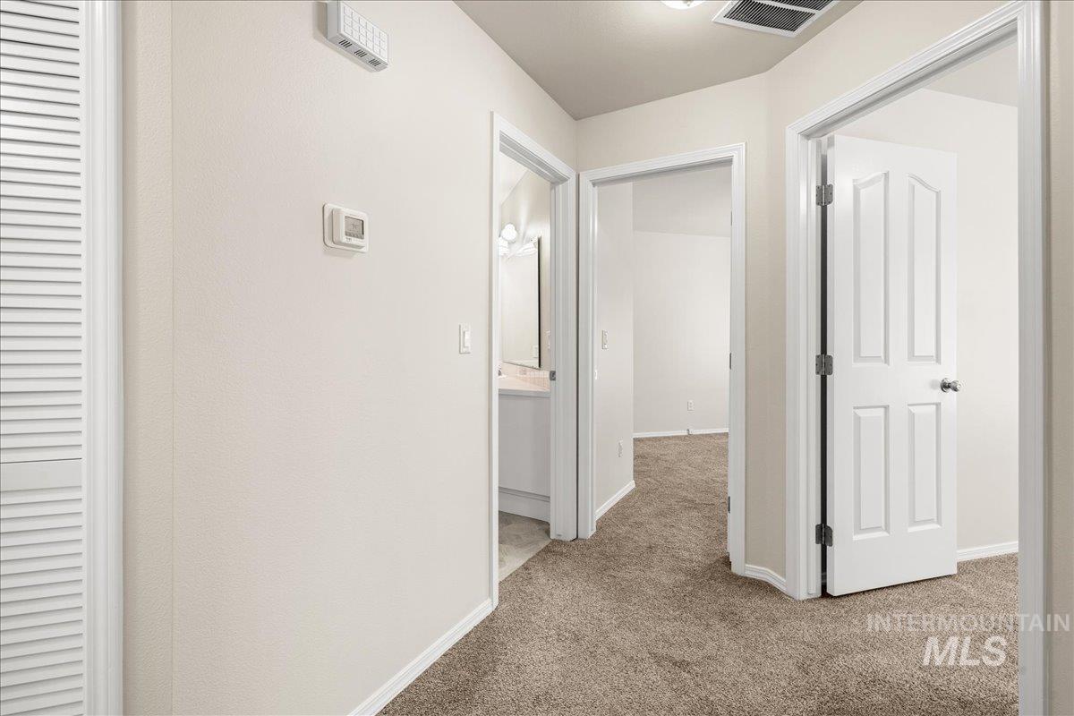 Hall featuring light carpet and baseboards