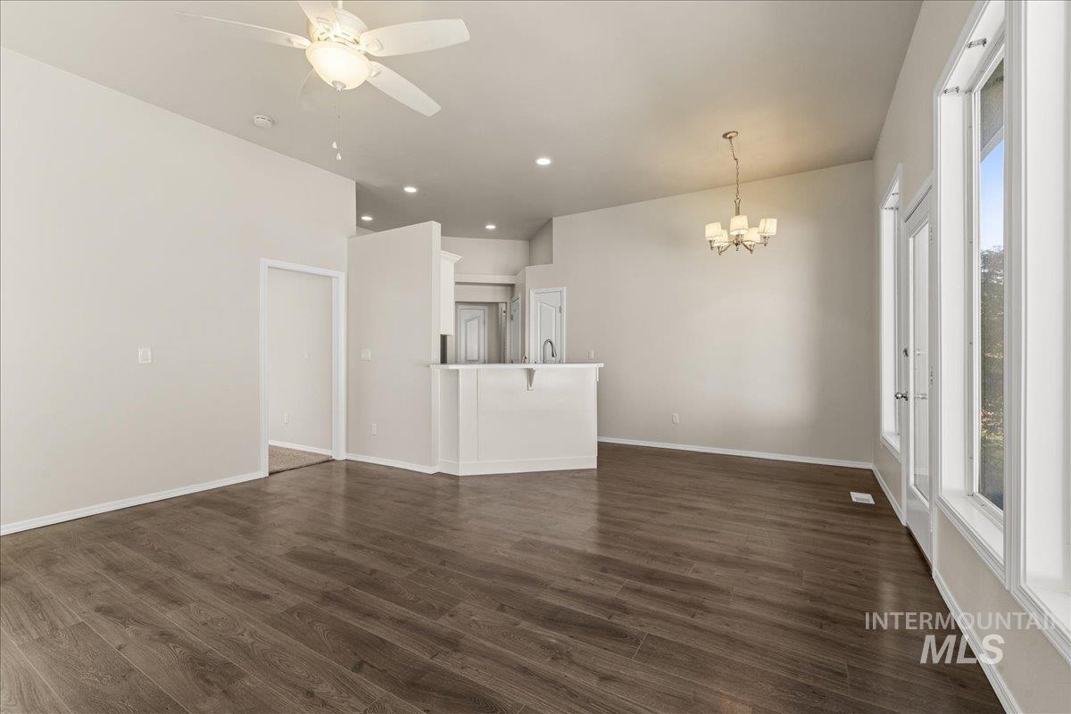 Unfurnished living room with dark wood-style floors, a chandelier, recessed lighting, and a ceiling fan