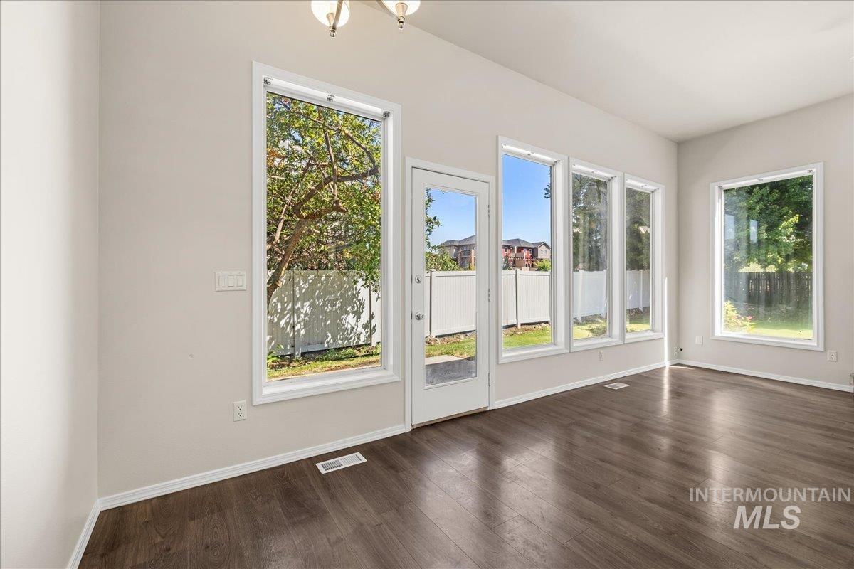 Doorway to outside with healthy amount of natural light, wood finished floors, and a chandelier