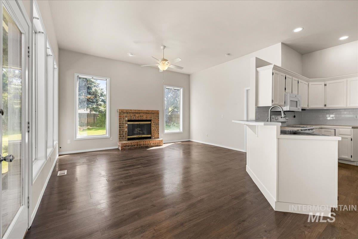 Kitchen featuring white cabinetry, decorative backsplash, open floor plan, dark wood finished floors, and recessed lighting