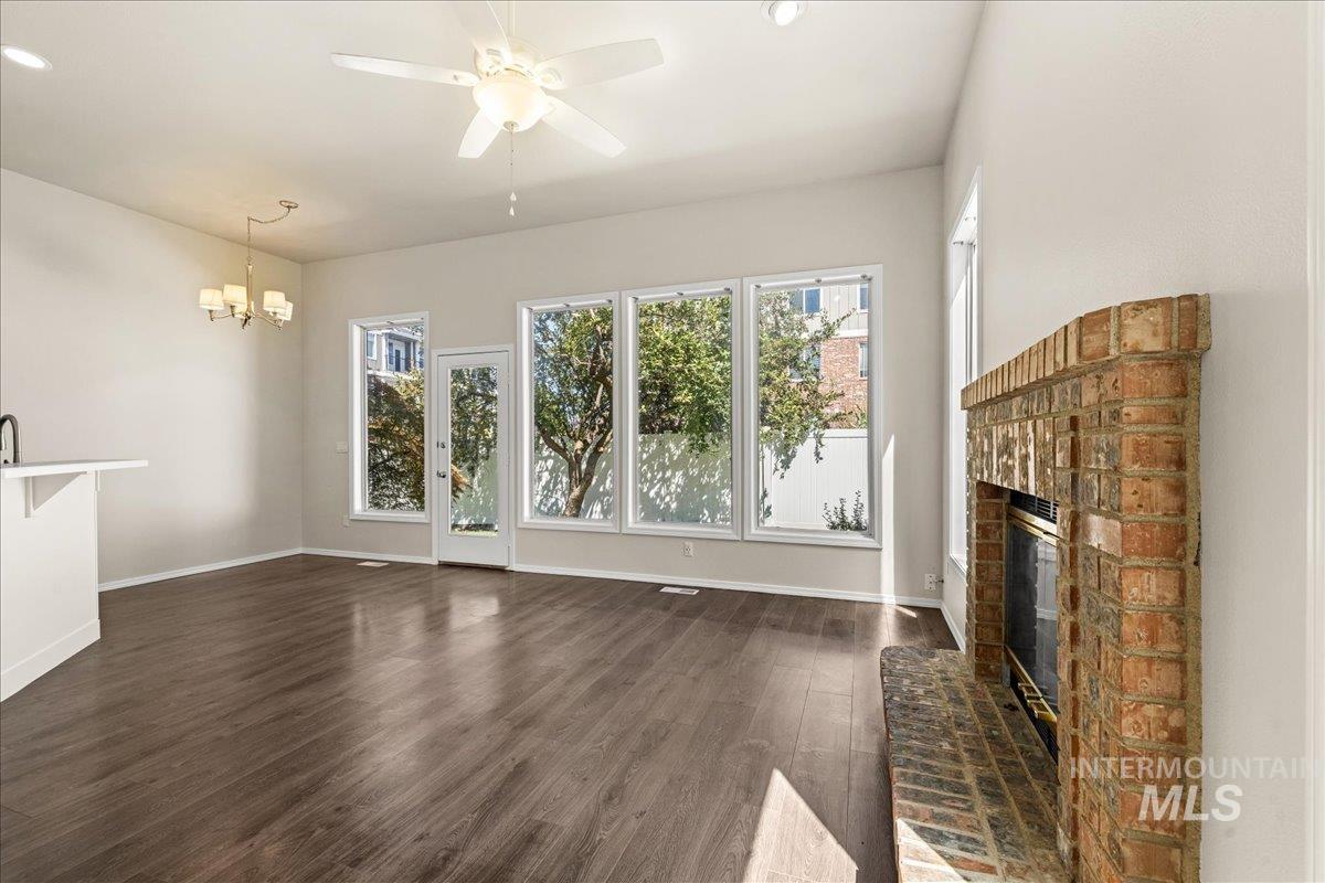 Unfurnished living room with dark wood-style flooring, a fireplace, a chandelier, recessed lighting, and ceiling fan