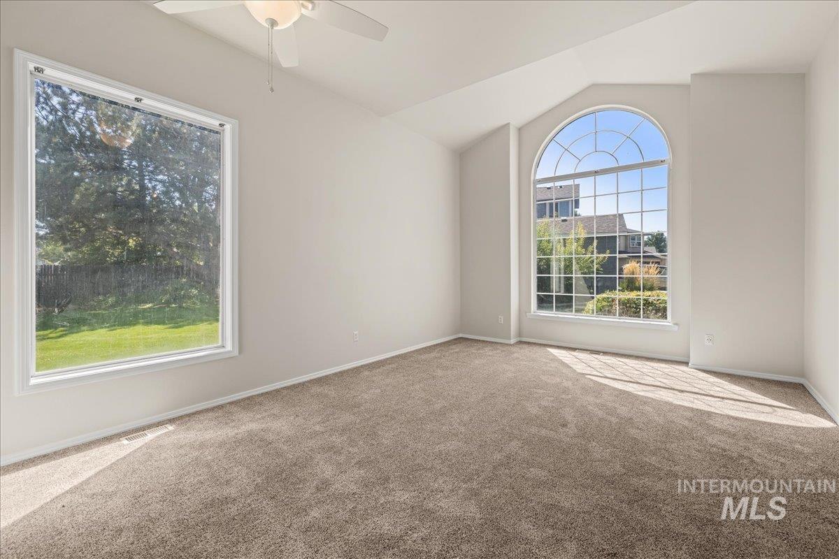Spare room with vaulted ceiling, carpet floors, and ceiling fan
