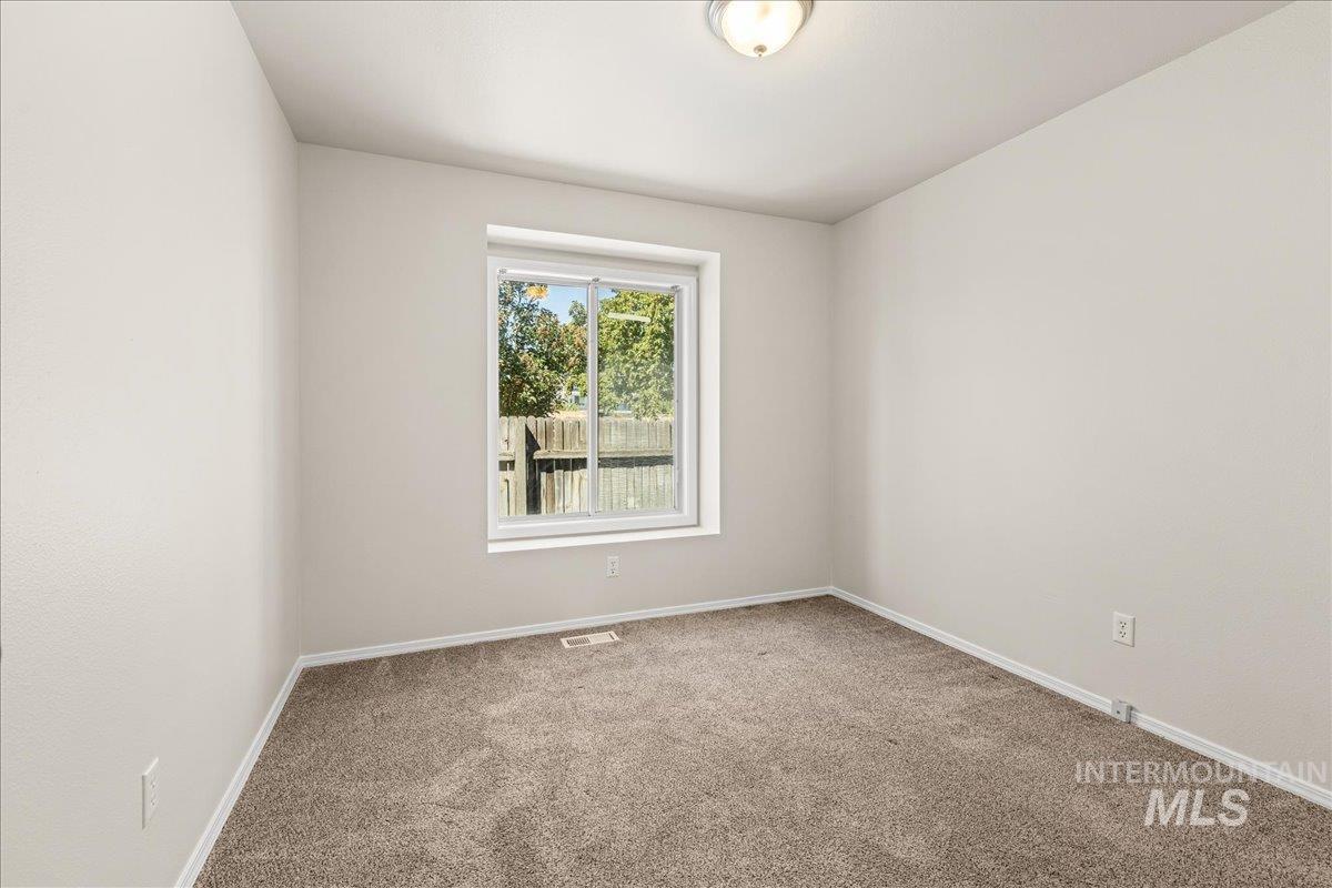 Empty room featuring light carpet and baseboards