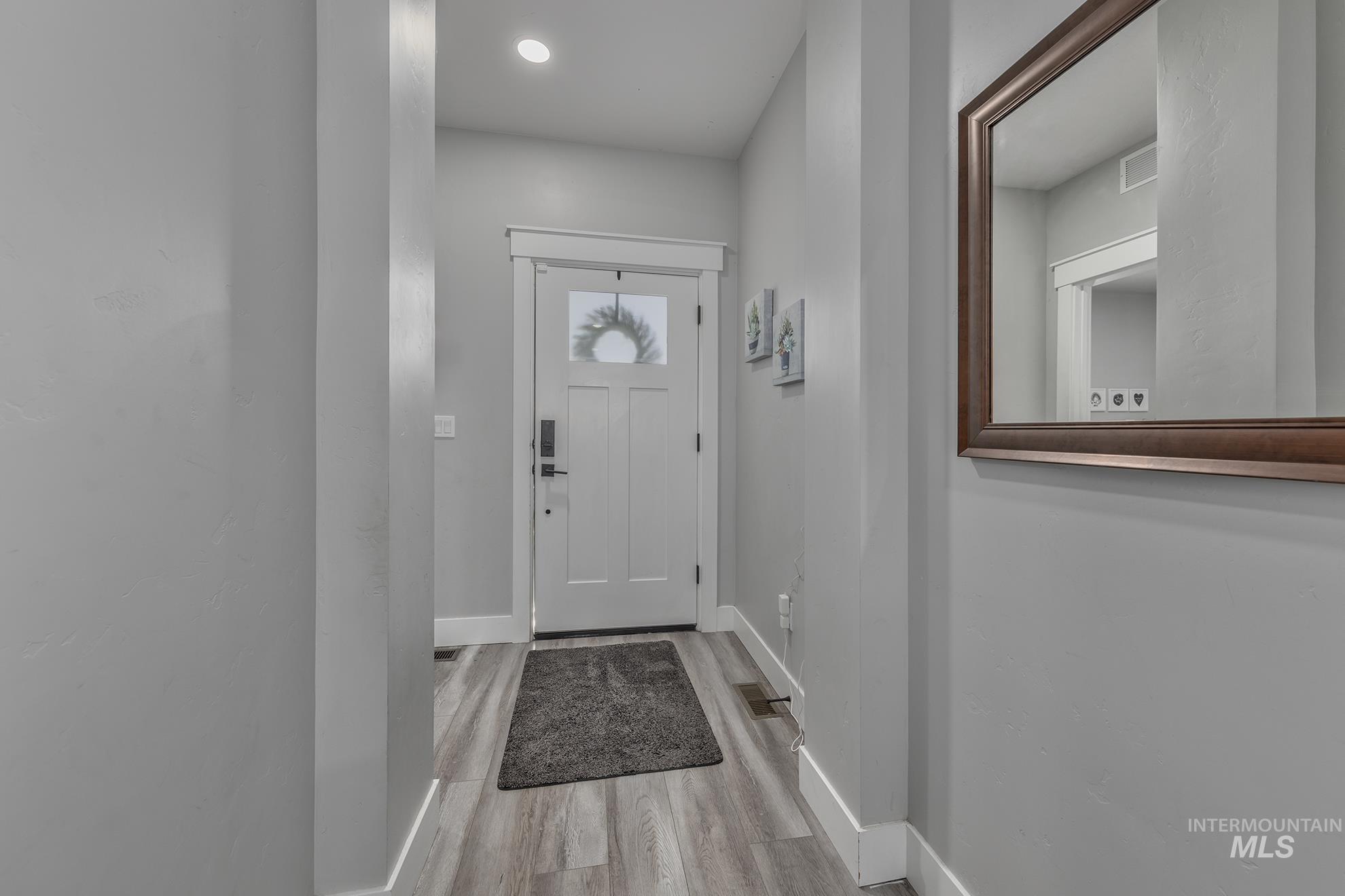 Doorway with baseboards and wood finished floors