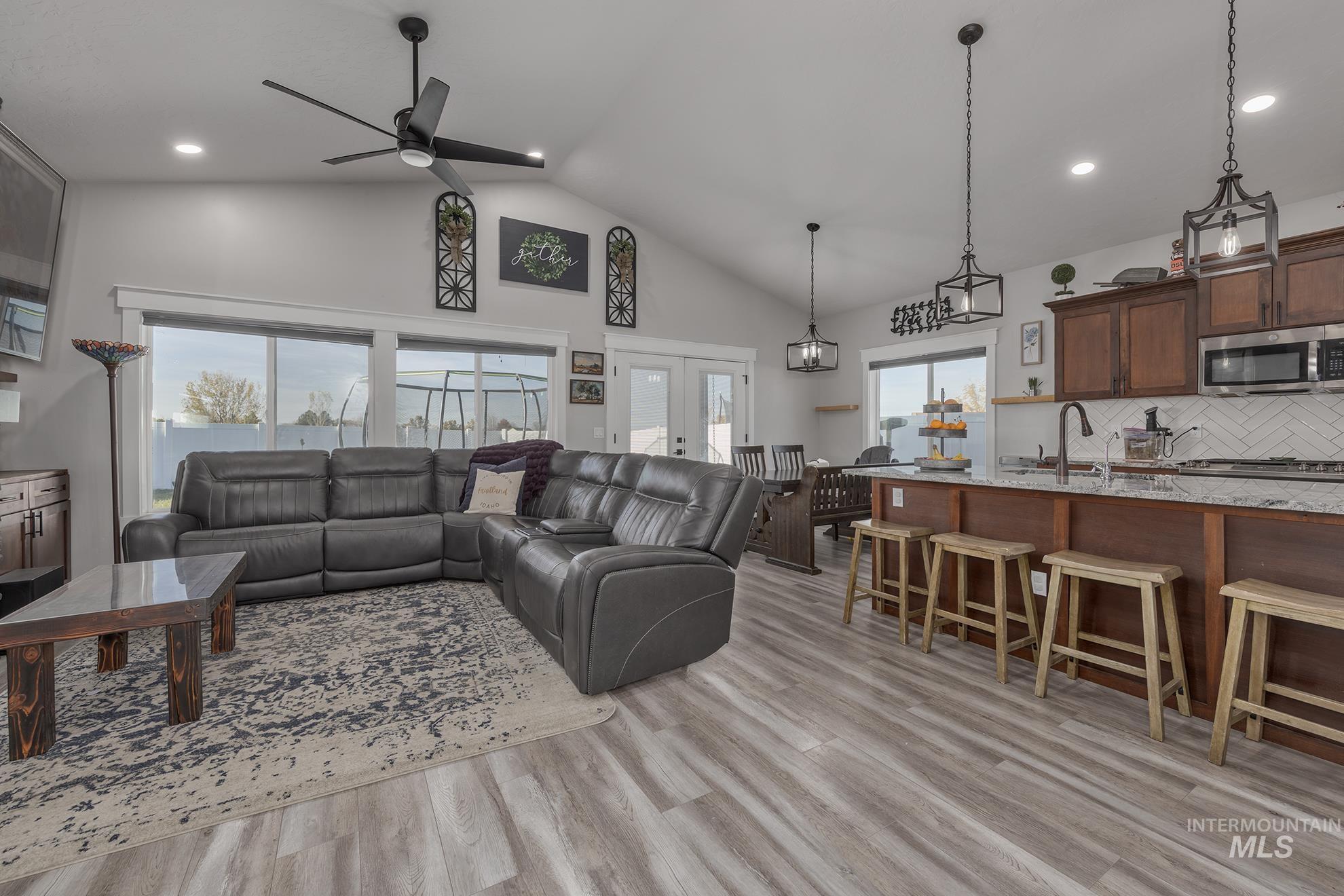 Living area with light wood-style floors, high vaulted ceiling, a ceiling fan, recessed lighting, and french doors