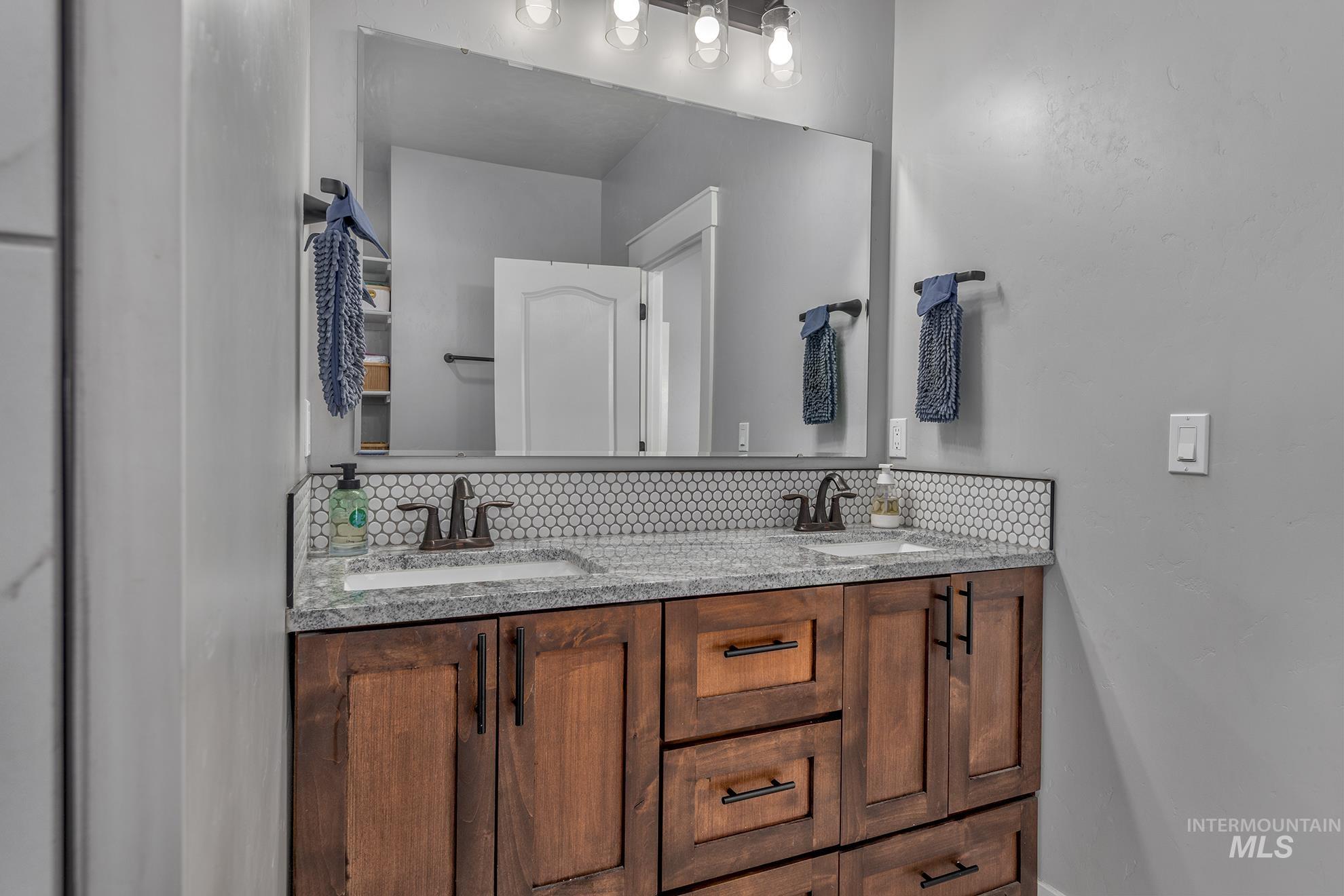 Full bathroom featuring double vanity and baseboards