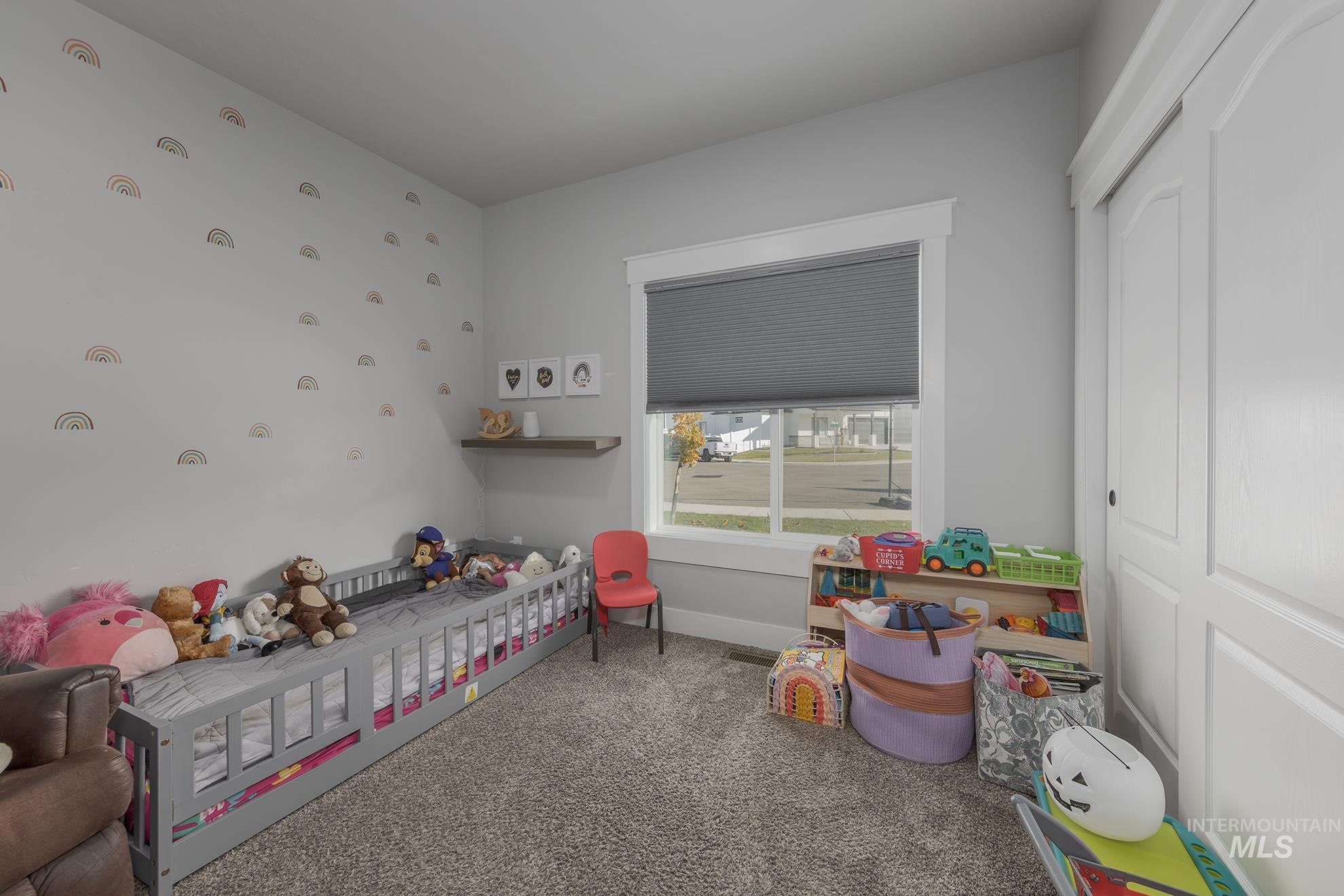 Carpeted bedroom with a closet and a crib