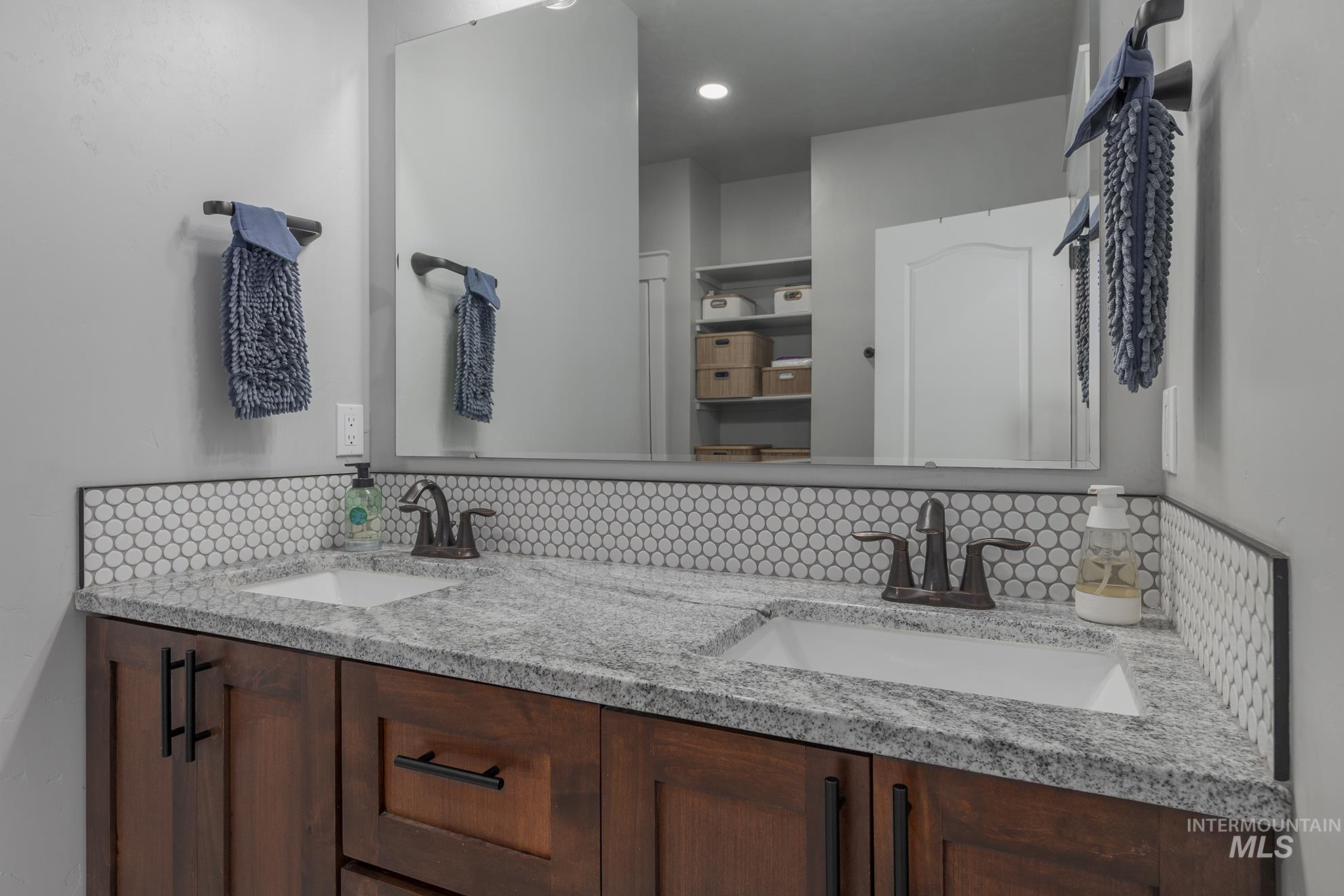 Bathroom featuring decorative backsplash and double vanity
