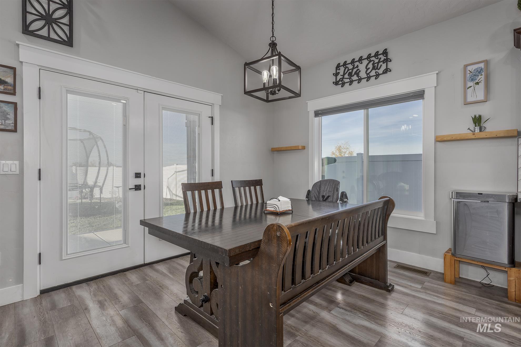 Dining room with french doors, wood finished floors, and a chandelier