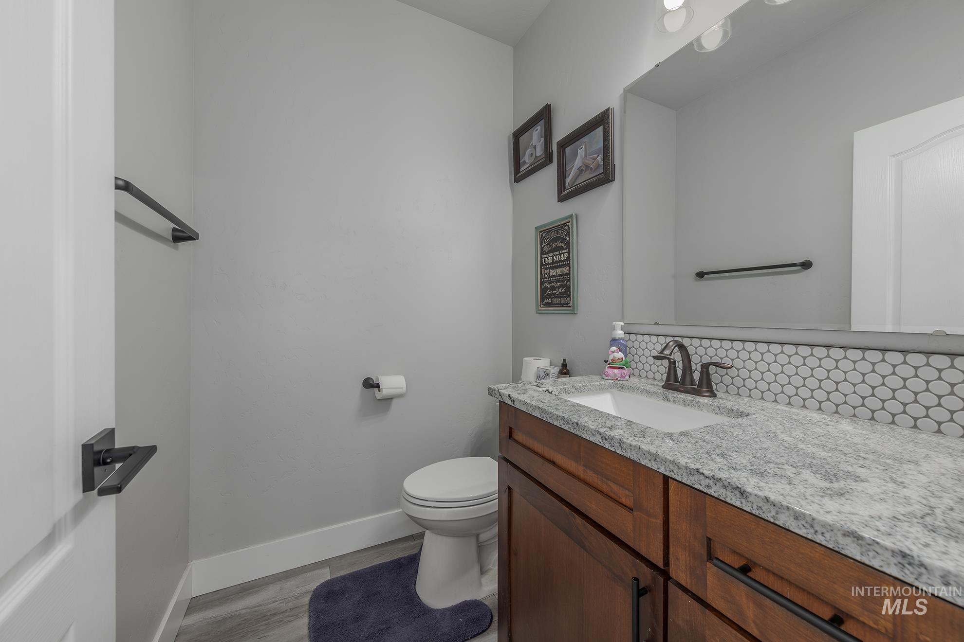 Bathroom with vanity, backsplash, and light wood finished floors