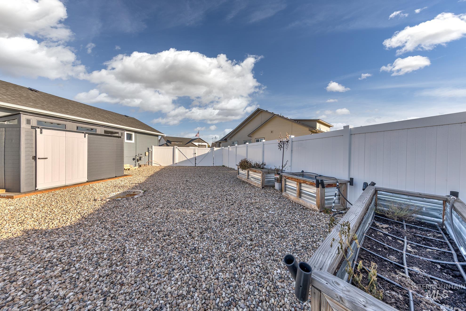 Fenced backyard with a vegetable garden and a gate