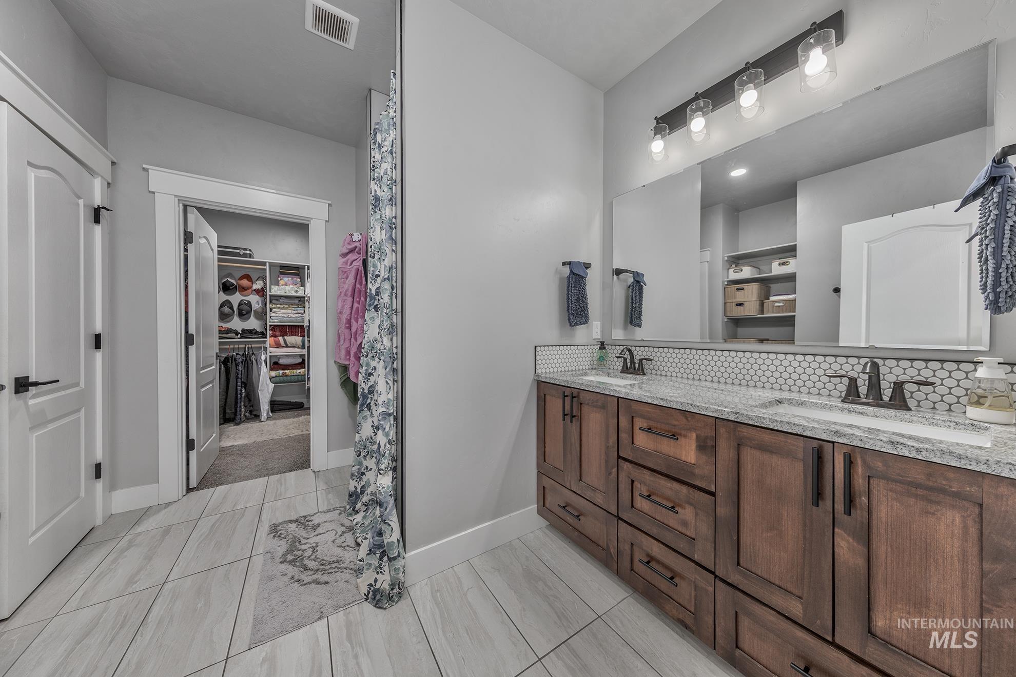 Bathroom with a spacious closet, double vanity, and backsplash