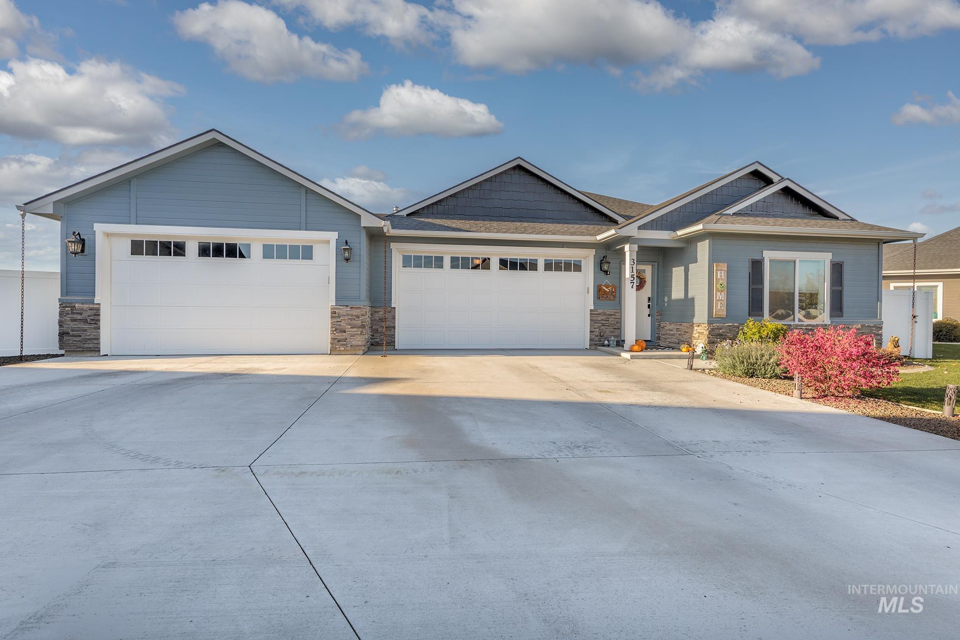 View of front of house with driveway, a garage, stone siding, and a shingled roof