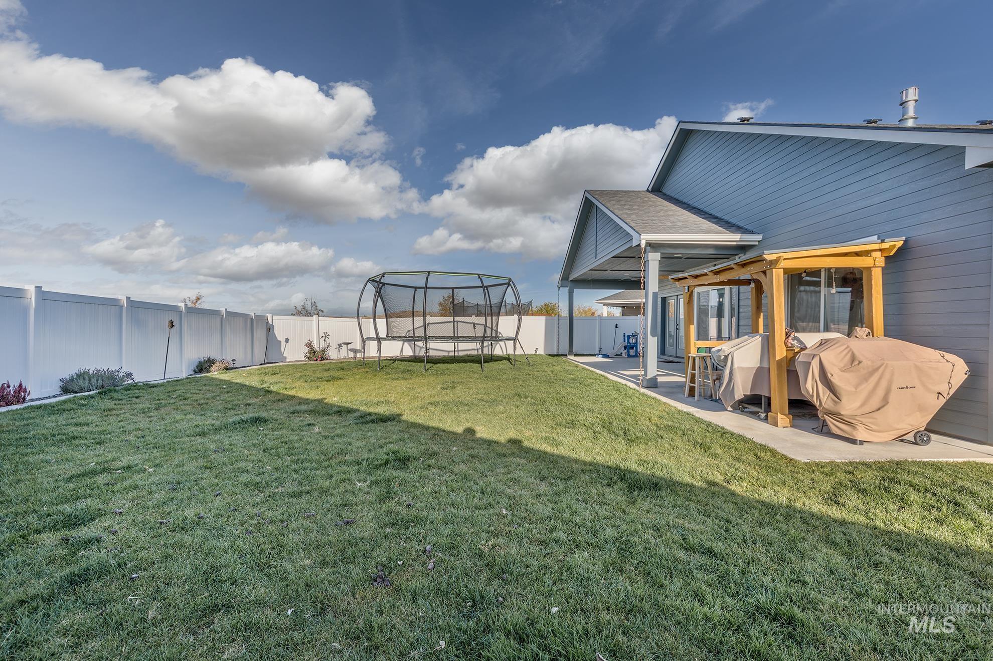 Fenced backyard with a trampoline and a patio