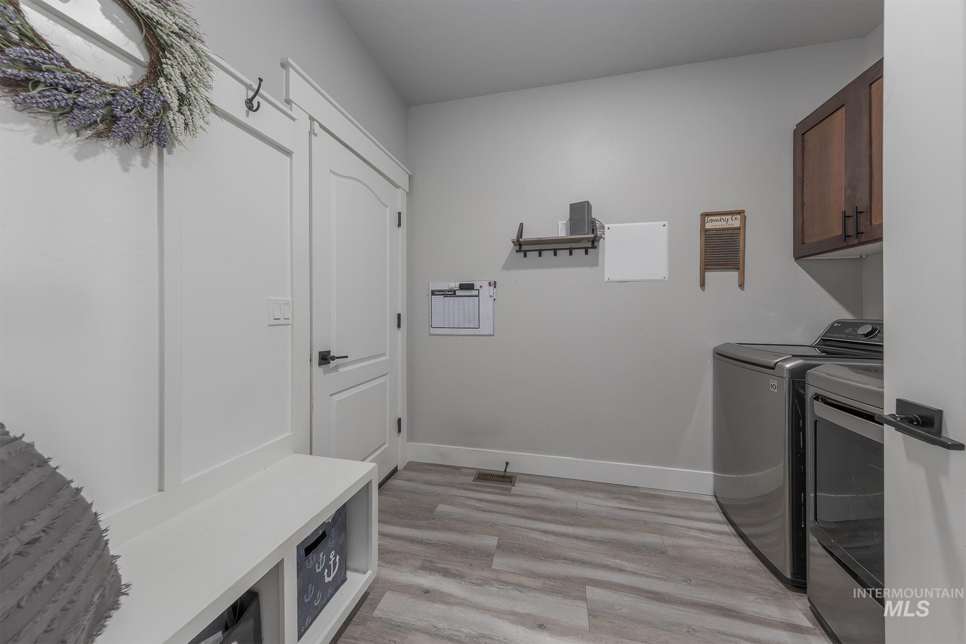 Laundry area with light wood-style floors, cabinet space, and washer and clothes dryer