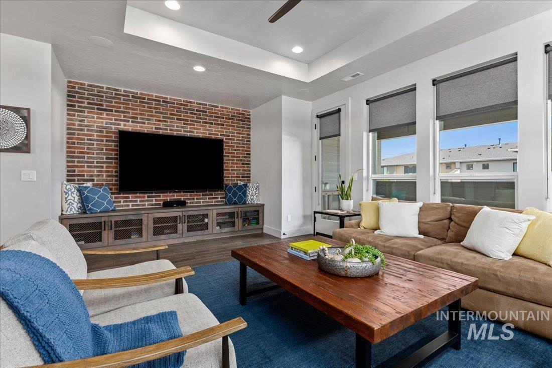 Living area featuring a raised ceiling, dark wood-style floors, recessed lighting, and ceiling fan