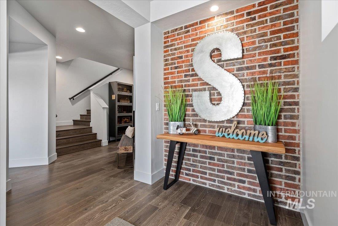 Entrance foyer featuring brick wall, stairway, recessed lighting, and dark wood-style flooring