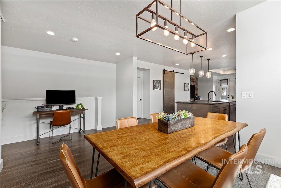 Dining room with a barn door, recessed lighting, and dark wood-style floors