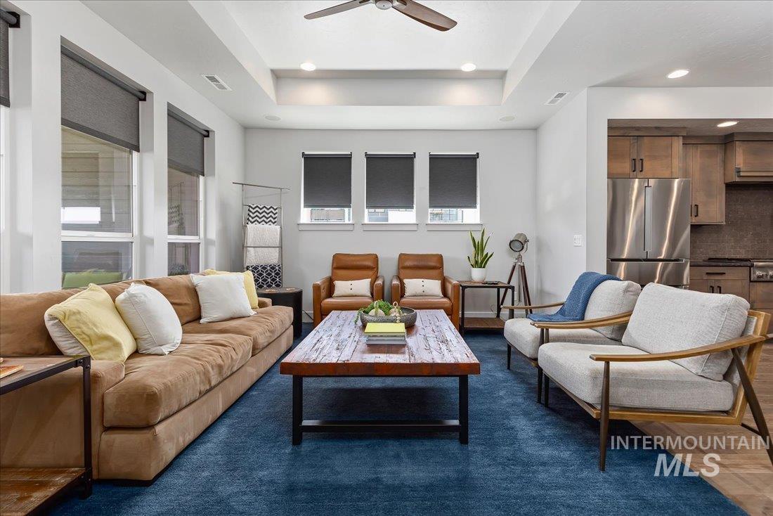 Living area with a ceiling fan, a tray ceiling, and recessed lighting