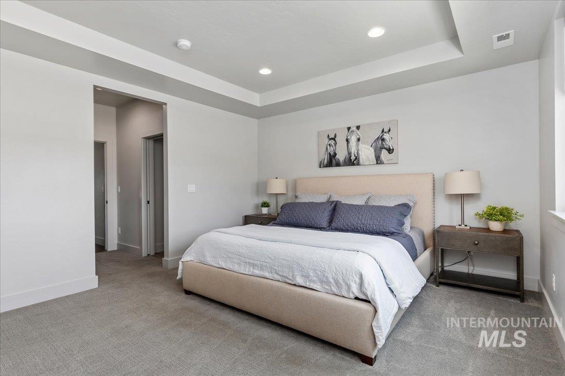 Carpeted bedroom featuring a raised ceiling and recessed lighting