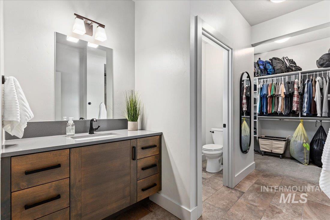 Bathroom featuring vanity, a spacious closet, and stone finish flooring