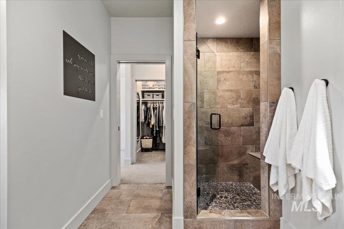 Full bath with stone tile floors, a spacious closet, and a shower stall