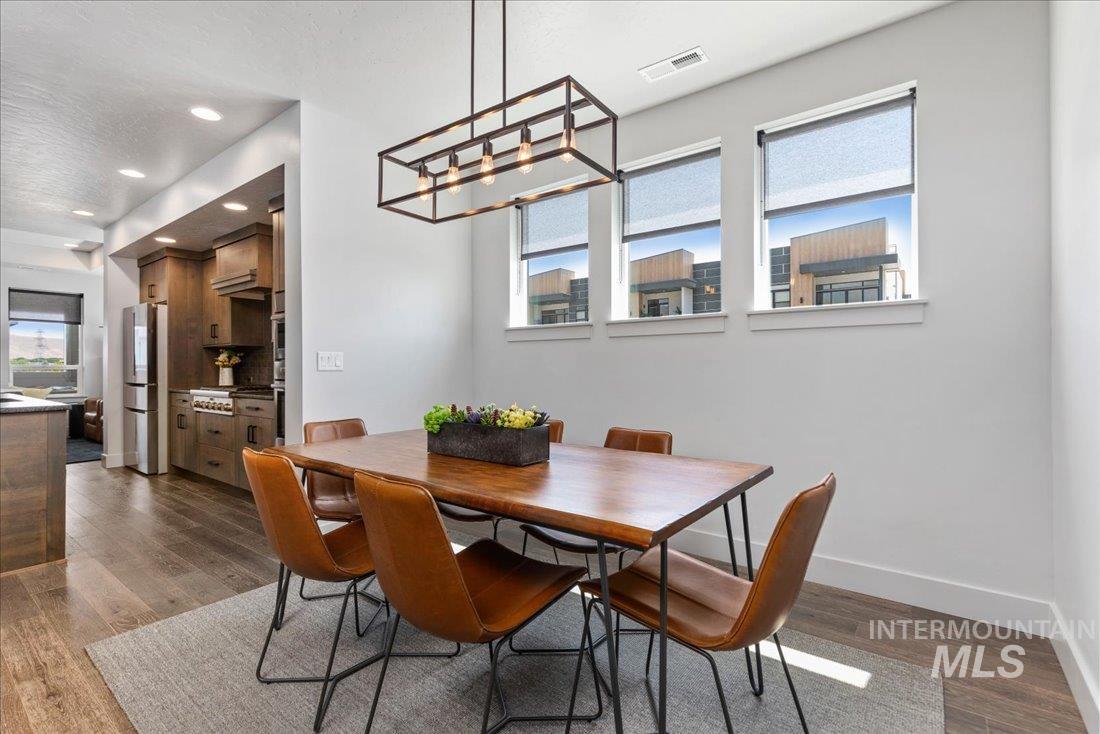 Dining space with dark wood finished floors, recessed lighting, and a chandelier