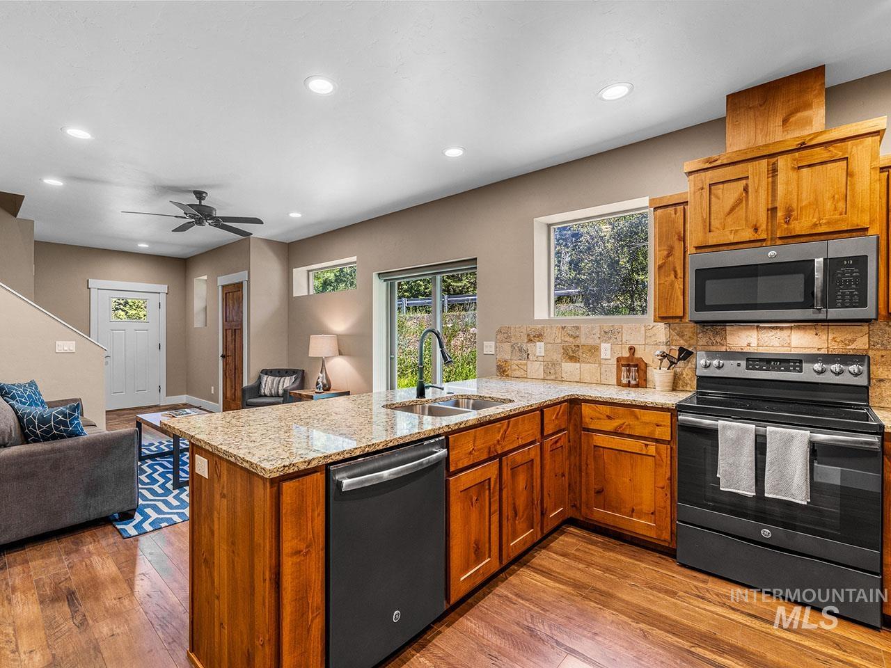 Kitchen featuring appliances with stainless steel finishes, a peninsula, open floor plan, brown cabinets, and recessed lighting